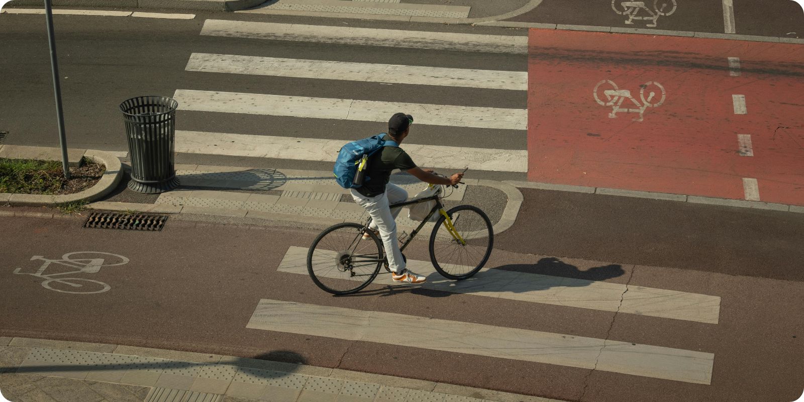 Cycliste pédalant sur une piste cyclable en ville vu du dessus.