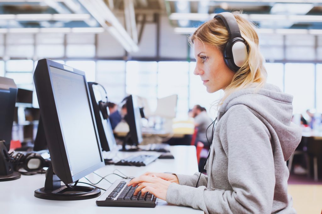 adult education, student in headphones working on computer in library